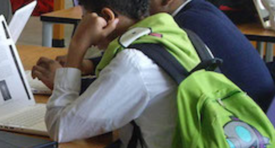 Photo of two males students at desk looking at something